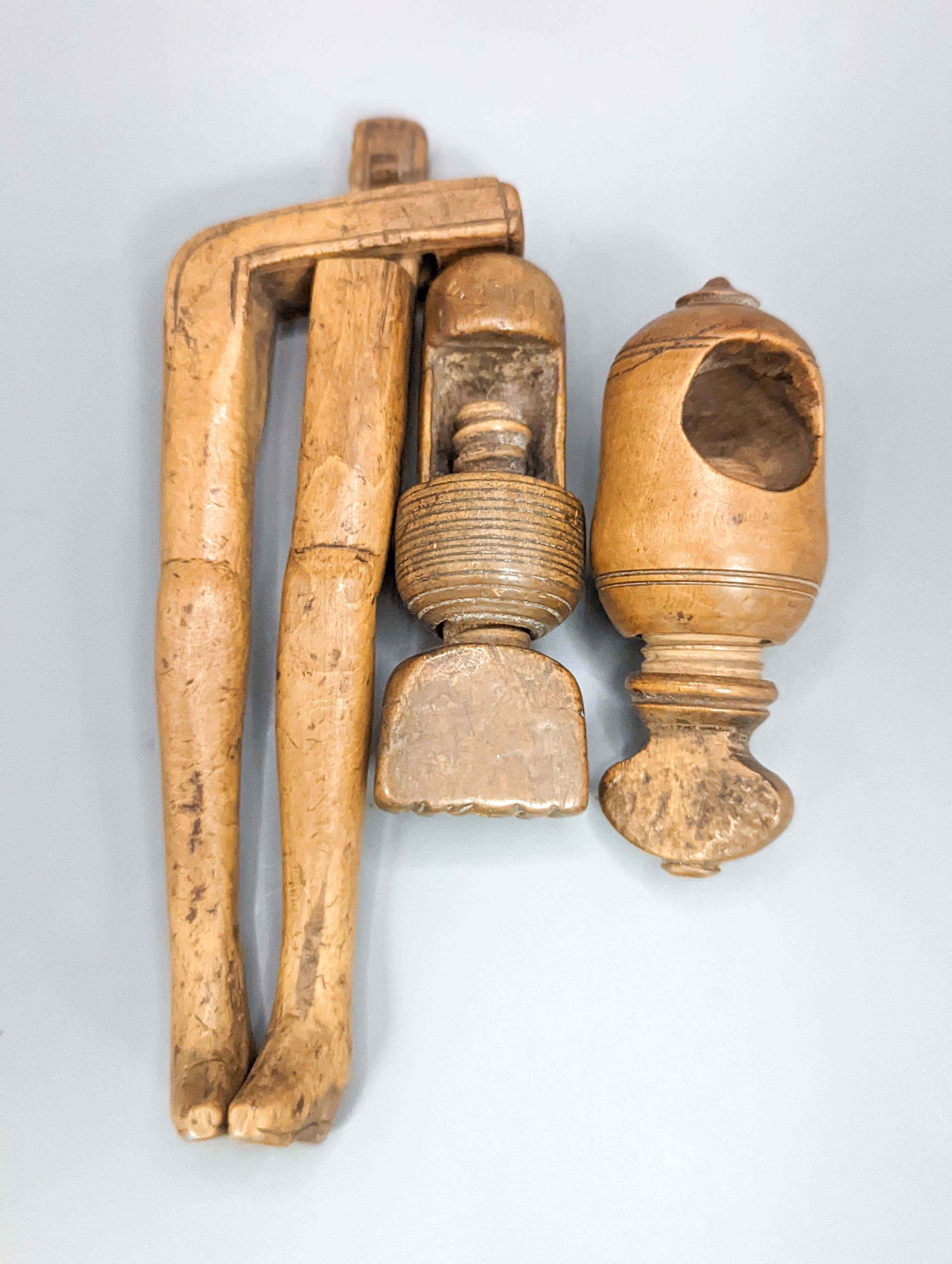 A pair of Georgian treen ‘riding boot’ nutcrackers, 14.5cm and two 19th century acorn-shaped Treen nutcrackers (3)